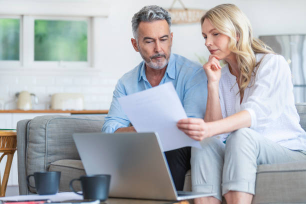 istock Happy mature couple using a laptop computer and doing paperwork on the sofa 1392204505