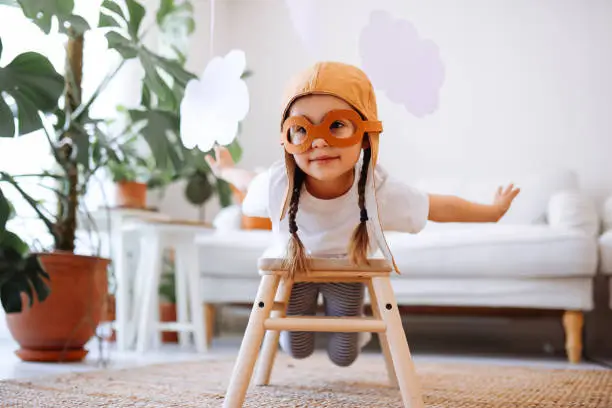 Photo of Little girl wearing a vintage pilot hat having fun at home