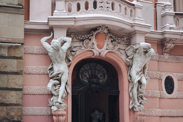 Ancient white stone caryatids in the form of male sculptures on the facade of the House of Scientists in Lviv. Baroque building with balcony. Winter and snow. stock photo