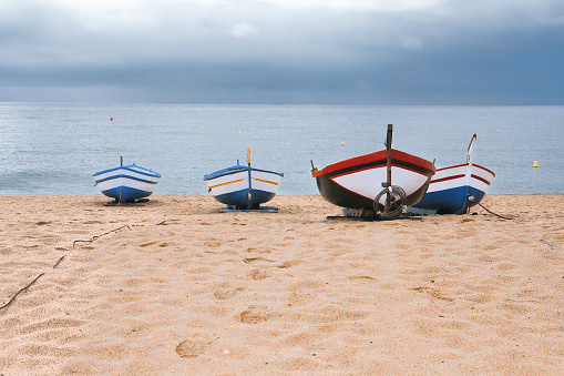 Close-up of four old fishing boats, washed up on the beach of Playa Gran in Calella, Costa del Maresme, Catalonia, Spain.