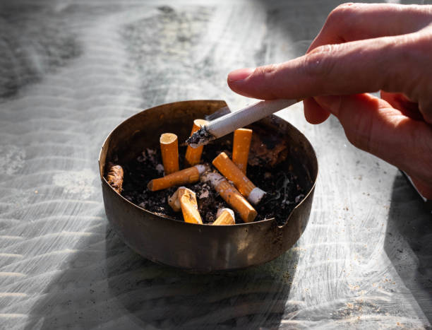 灰皿に灰を叩くタバコを握る手 - 喫煙問題 ストックフォトと画像