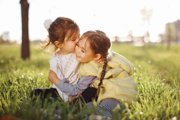 Family value. Two sisters in the Park on the grass met, look into the distance, have fun.