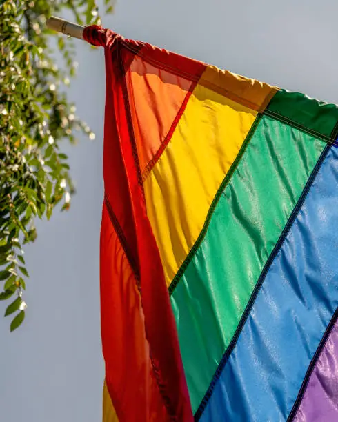 A gay pride flag hangs in front of a store.