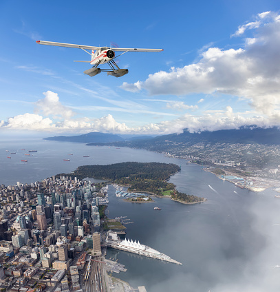 Seaplane flying over Downtown Vancouver during a sunny summer day. 3d rendering airplane. Aerial View of the modern city on the West Coast of British Columbia, Canada.