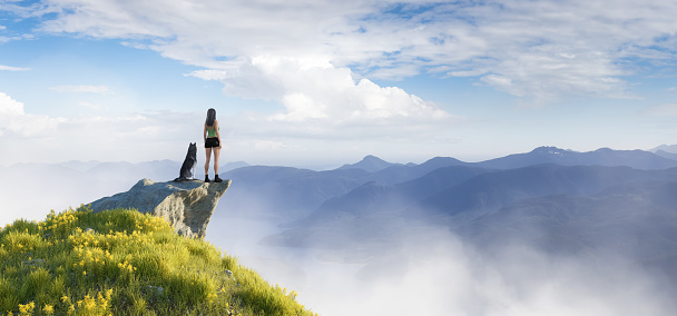 Adventurous Woman Hiking on top of a mountain with a Husky dog. 3d Rendering Adventure Artwork. Aerial nature landscape Image from British Columbia, Canada.