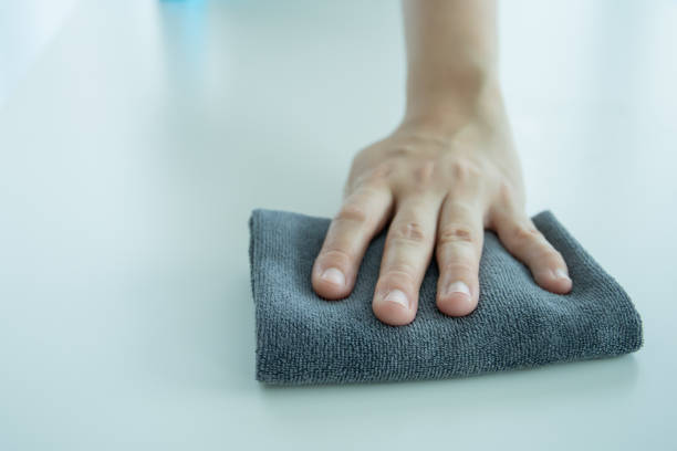 istock Woman - housewife using microfiber with sanitizer to clean table surface. 1392234602
