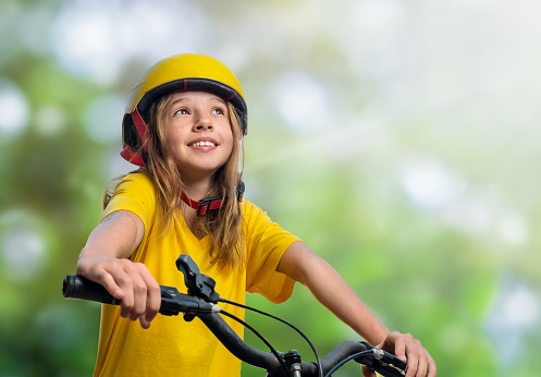 Portrait of a teenager girl in a helmet on a bicycle outdoor