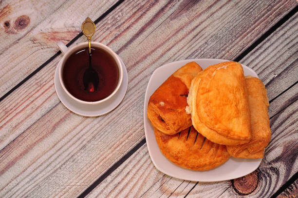 istock Puff curd buns on a ceramic plate and a cup of black tea on a wooden table. 1392244590