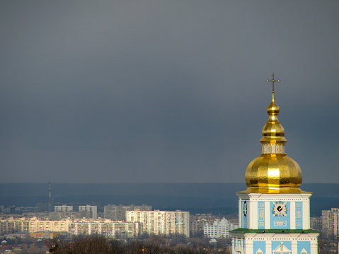 Golden bell tower of Saint Michael's Monastery in central Kyiv and a residential district in the distance.  This image was taken on an afternoon in Spring.