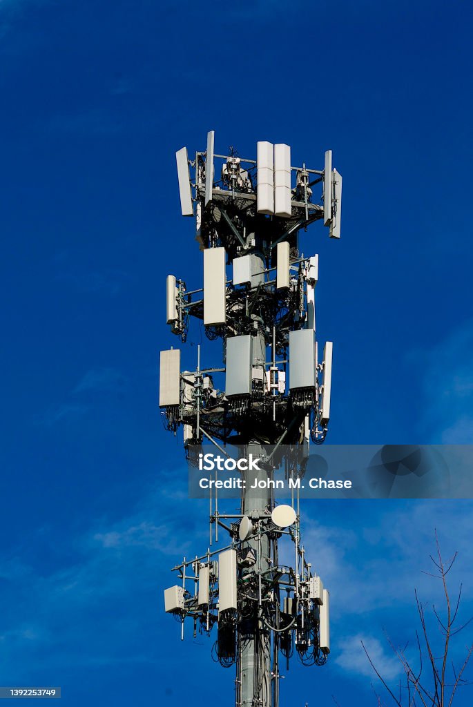 Communications Tower A communications tower with multiple cellular antennae and related tele-communications equipment stands out against a blue sky. 5G Stock Photo