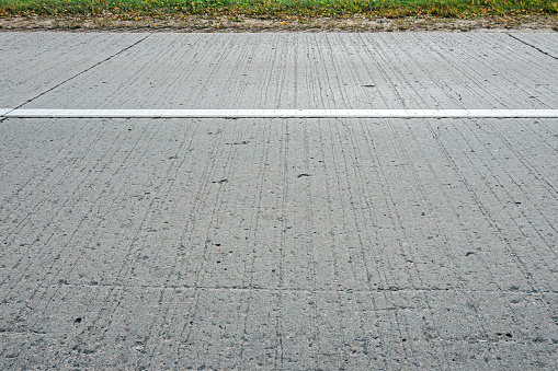 gray concrete country road with white dividing line. closeup side view.