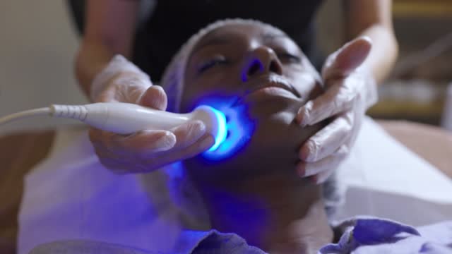 African American woman at the spa getting a rejuvenation treatment on her face using ultrasound and light therapy