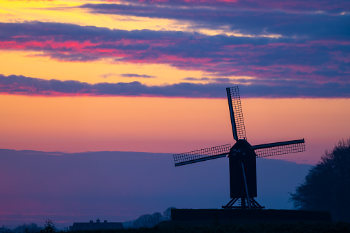 This beautiful Mountain mill is located in Wannegem-Lede Belgium, with the rise of the sun and  clouds.