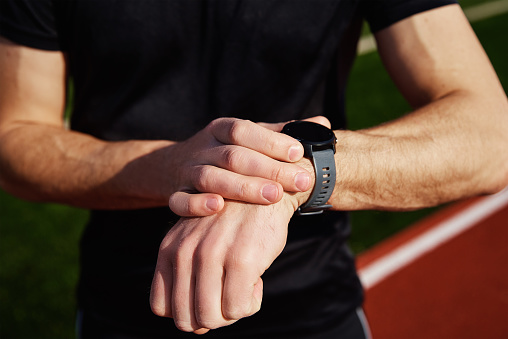 Man checking fitness watch after exercises at stadium rack