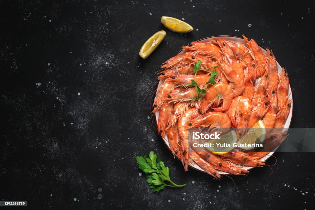 Boiled tiger prawns in a plate on a black stone background. Red shrimp. Top view, flat lay, Shrimp - Seafood Stock Photo