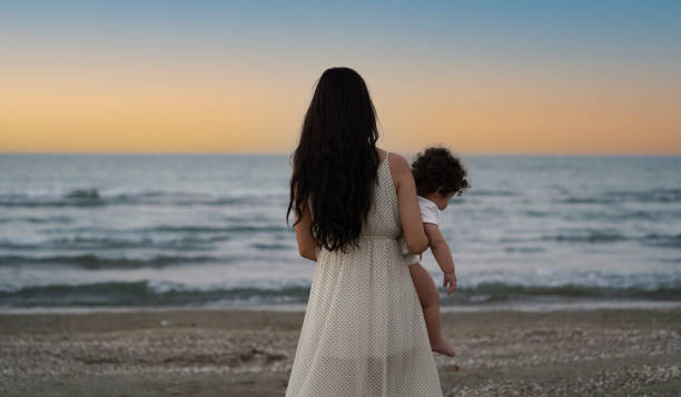 istock Mother and daughter having fun at the beach at sunset 1392267112