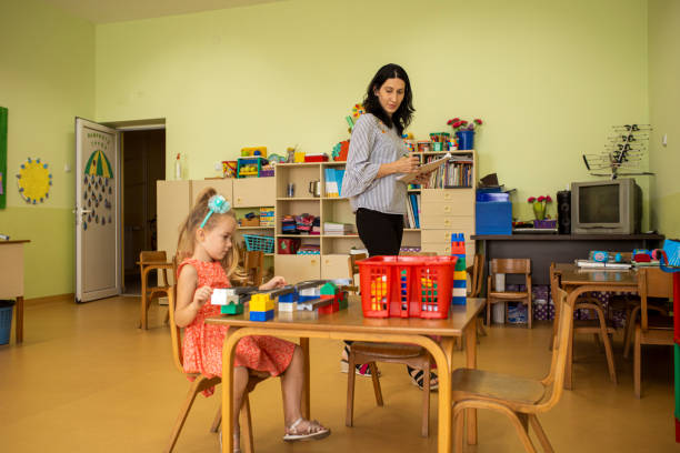 Lovely girl having fun with her nanny, while making some interesting shapes with plasticine