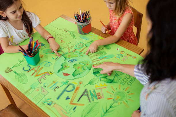 istock Caring preschool teacher using the poster to teach her students about responsibility for the good of Earth 1392268241