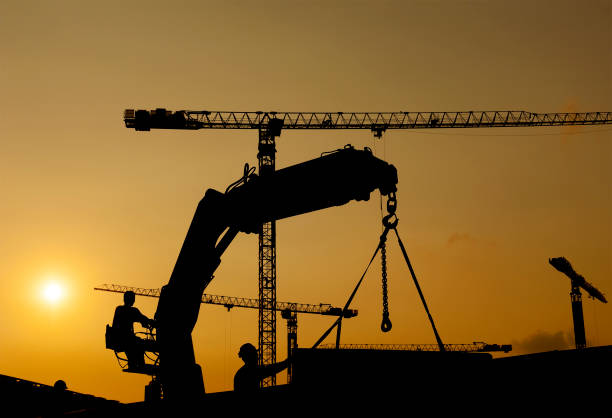 istock Silhouette of worker and crane in construction site 1392269529