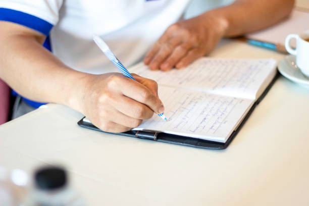 istock hand holding pen  closeup to write or signature on white paper to take note with copyspace 1392269839