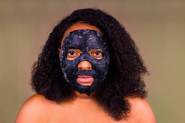 istock Young woman with bubble sheet mask on her face on brown background 1392273045