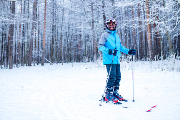 afro american man in blue jacket run ski outdoors in freeze forest .