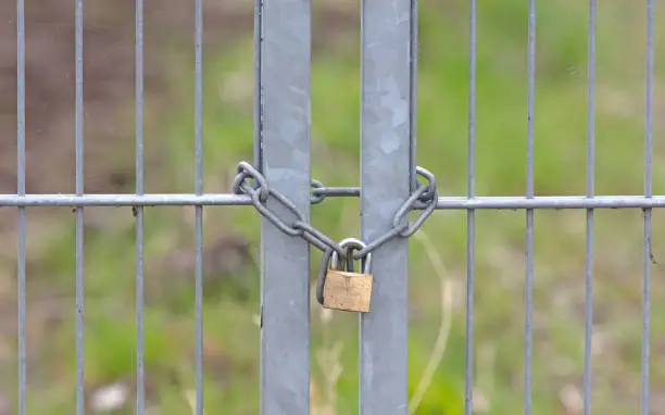 Photo of Large metal fence locked with a padlock and a chain