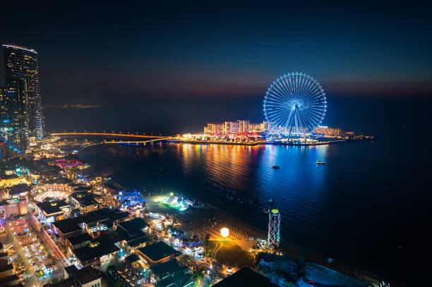 Bluewaters island leisure spot in Dubai with large Ferris wheel seen from JBR beach in Dubai Marina area Bluewaters island leisure spot in Dubai with large Ferris wheel seen from JBR beach in Dubai Marina area at night. United Arab Emirates travel destination biggest stock pictures, royalty-free photos & images