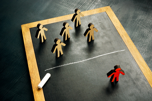 Social exclusion concept. Figurines and chalk line separating them.