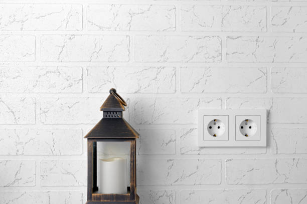 On the white building wall there is an empty double rosette, next to an old lantern with a candle. Turn off the lights.