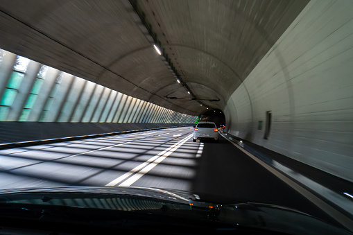 Car driving through an illuminated tunnel. Blurry long exposure of traffic. Inside point of view, no people.