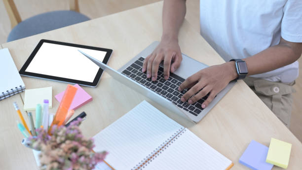 istock Cropped shot male office worker using laptop computer on wooden table. 1392278428