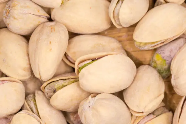 Heap of the roasted salted pistachio nuts with partly open shells, top view close-up in selective focus