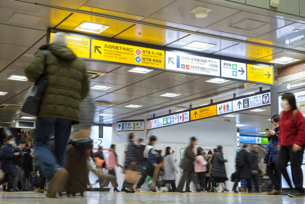 Crowd of people walking and direction signs in Tokyo Railway Station stock photo