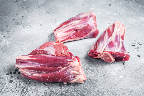 istock Uncooked Raw lamb shanks, mutton meat on kitchen table. Gray background. Top view 1392281543