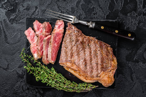 istock Griiled on BBQ sliced Striploin marbled beef meat steak. Black background. Top view 1392282439
