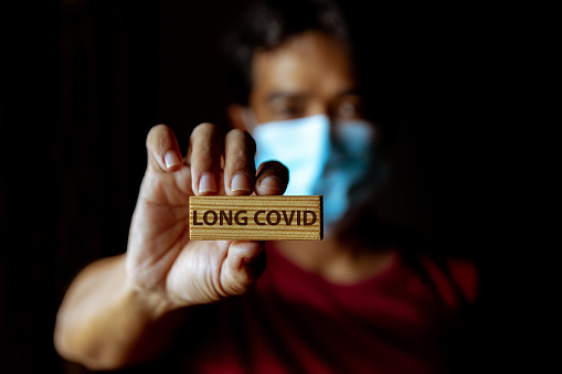 Hombre asiático enmascarado muestra letrero de madera con la frase 