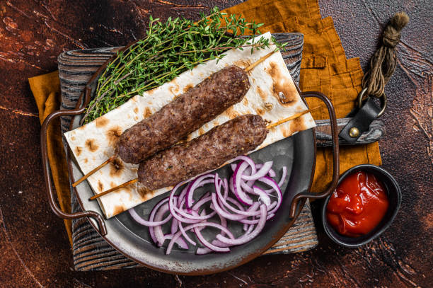 kebab turc adana à partir de viande de bœuf d’agneau haché sur brochette avec pain plat et oignon. fond sombre. vue de dessus - lamb kebab kofta ground photos et images de collection