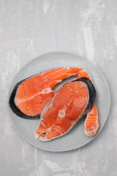 istock raw fresh salmon on ceramic plate on blue 1392284650