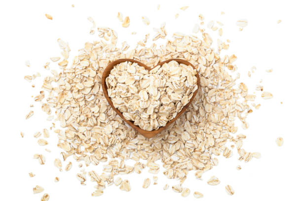 haferflocken, rohe haferflocken in herzförmiger holzschale - oatmeal oat heart shape rolled oats stock-fotos und bilder