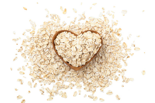 fiocchi d'avena, farina d'avena cruda in ciotola di legno a forma di cuore - oat oatmeal rolled oats oat flake foto e immagini stock