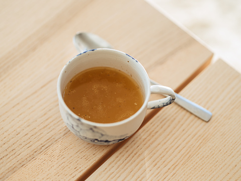 Chicken bone broth in a cup with spoon\nHealthy eating concept of bone broth keto diet must