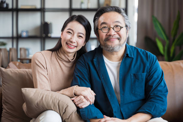 азиатская азиатская пара средних лет улыбается в камеру. портрет семейной пары - middle human age couple women стоковые фото и изображения