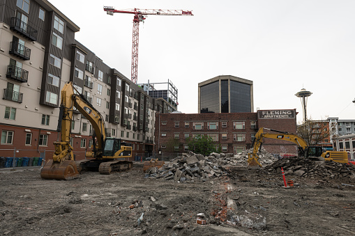 Seattle, USA - Apr 6th, 2019: Construction equipment and a demolished building in Belltown with the Space Needle in the background late in the day.