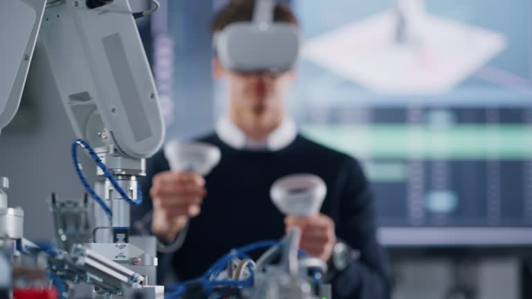 Male Student in VR Googles Lifting and Moving Bionic Hand wit Controllers while Doing his Project at the University. Computer Science and Education Concept