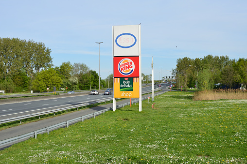 Drongen, Oost-Vlaanderen Belgium - April 18, 2022: highway E40 From Brussels to Ostend, Blankenberge. Advertisement Esso gas station, Louis Delhaize food market and American chain fastfood Burger King