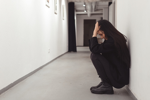 Stressed overworked young business woman sitting on floor. Fired and feeling depression in workplace of office.