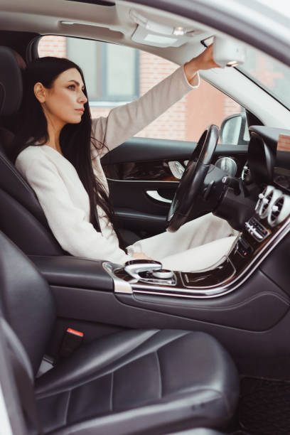 istock Pretty young woman setting rearview mirror before driving her modern car, transportation concept 1392290532