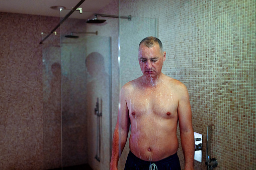 A caucasian adult male taking a shower at spa center.