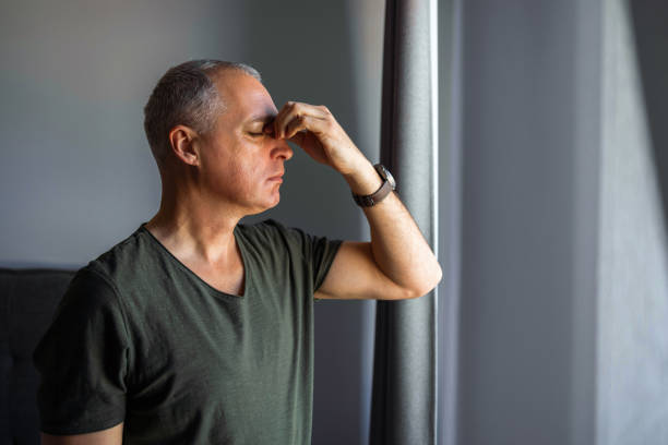 Depressed  man standing by the window i